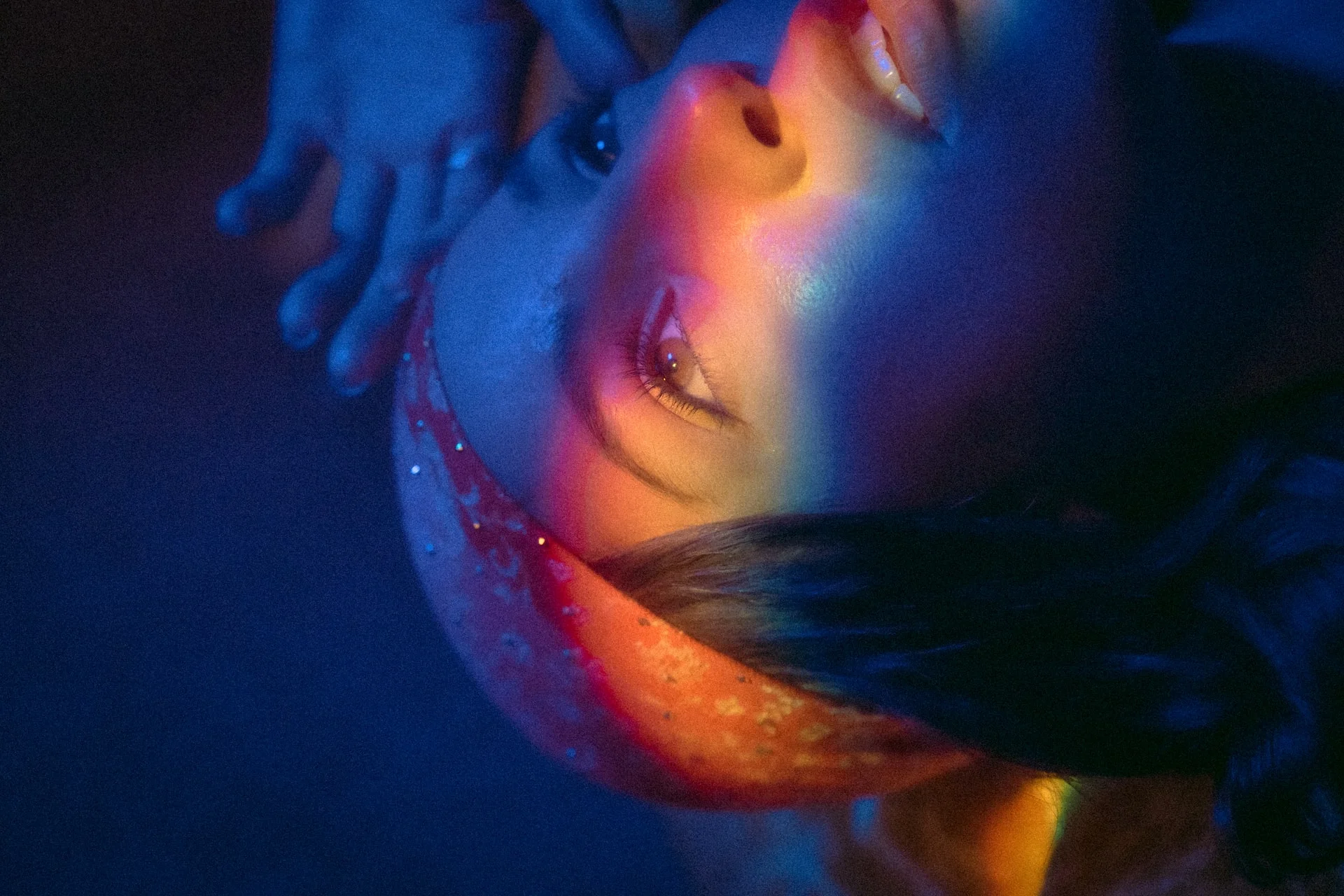 Girl looking up with a rainbow light across her face